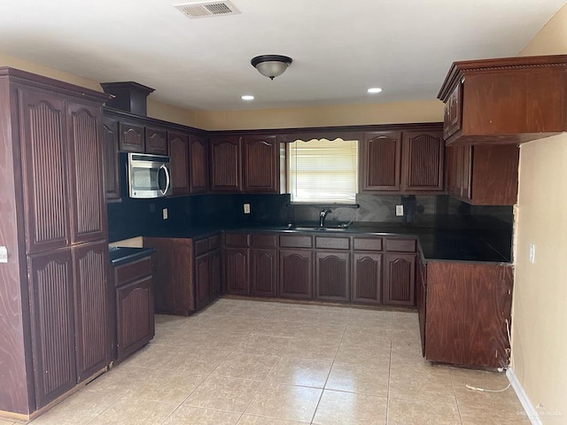 kitchen with backsplash, dark brown cabinets, light tile patterned floors, and sink