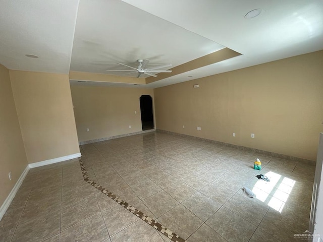 unfurnished room with ceiling fan and a raised ceiling