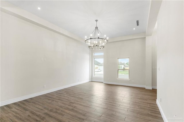 empty room featuring a notable chandelier and dark wood-type flooring