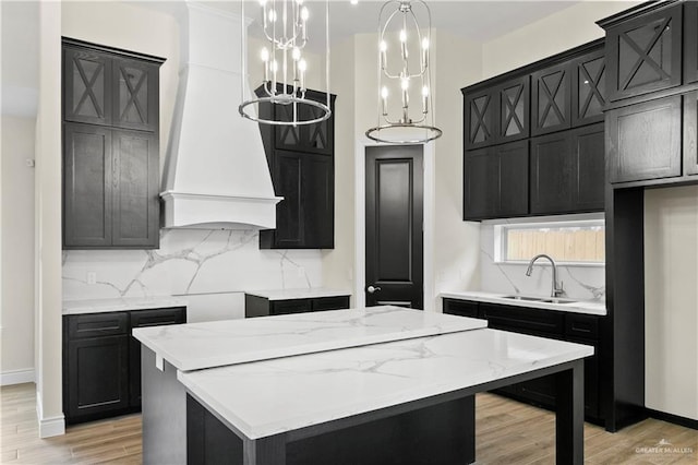 kitchen with light wood-type flooring, pendant lighting, a center island, and sink