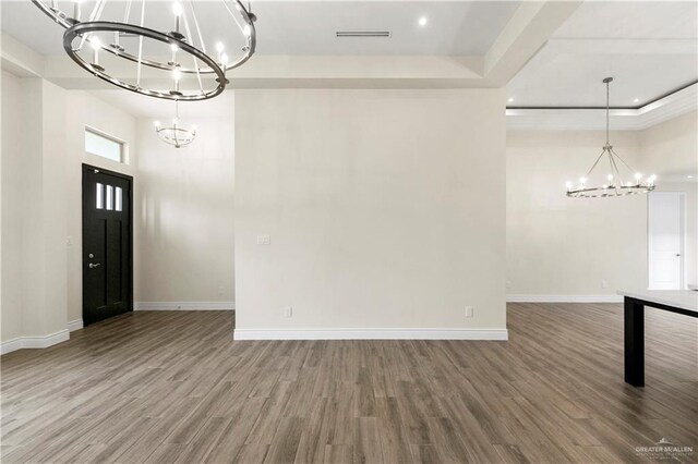 interior space with a chandelier, wood-type flooring, a towering ceiling, and a tray ceiling