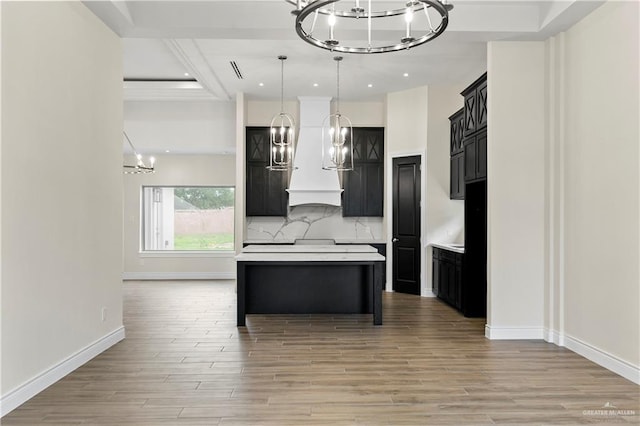 kitchen with a center island, an inviting chandelier, light hardwood / wood-style flooring, decorative light fixtures, and decorative backsplash