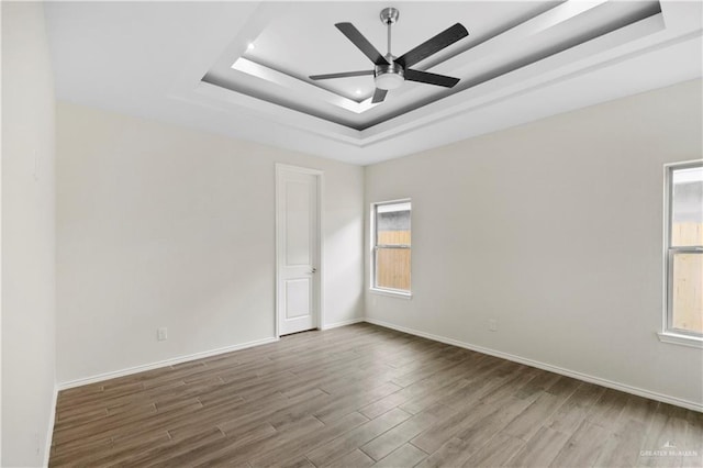 unfurnished room with hardwood / wood-style floors, ceiling fan, and a tray ceiling