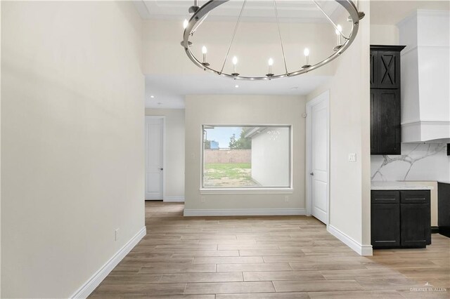 unfurnished dining area with a chandelier and light hardwood / wood-style floors