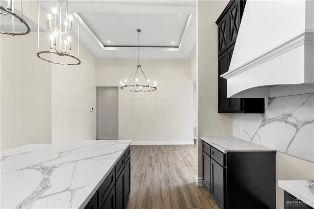 kitchen featuring pendant lighting, a raised ceiling, dark hardwood / wood-style floors, light stone countertops, and custom range hood