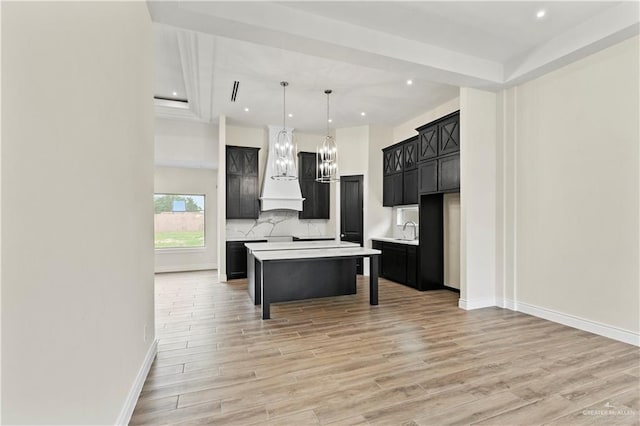 kitchen featuring a kitchen bar, custom range hood, a center island, and light hardwood / wood-style flooring