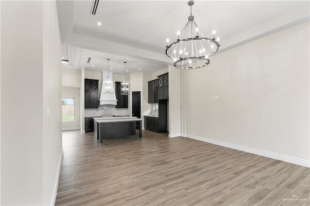 kitchen with a center island, hanging light fixtures, custom range hood, and wood-type flooring