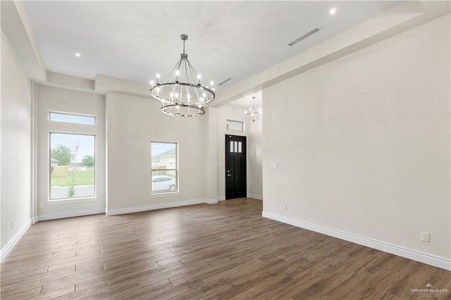 spare room featuring hardwood / wood-style flooring and a chandelier