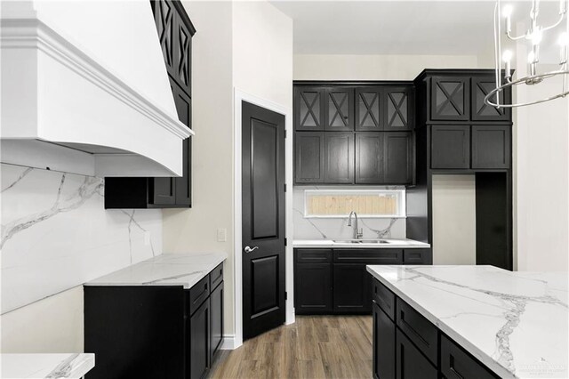 kitchen with decorative backsplash, custom exhaust hood, sink, hardwood / wood-style floors, and hanging light fixtures