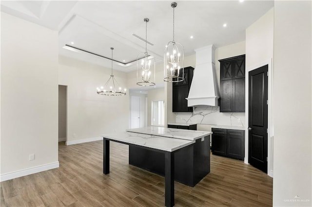 kitchen featuring a breakfast bar, a center island, custom range hood, decorative light fixtures, and wood-type flooring