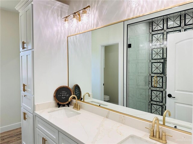 2201 Blue Sky Dr, Weslaco, TX 78599 - bathroom featuring double vanity, toilet, wood finished floors, and a tile shower