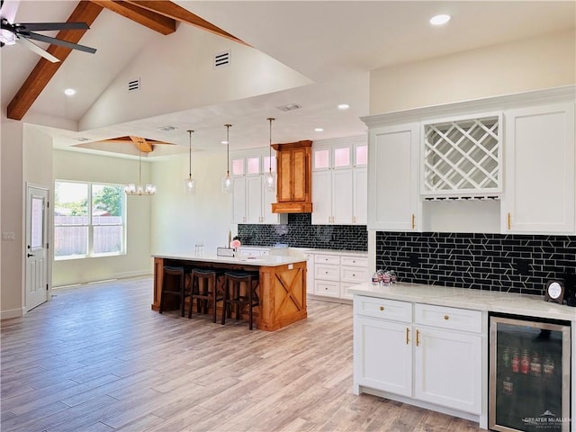 2201 Blue Sky Dr, Weslaco, TX 78599 - kitchen with wine cooler, light countertops, white cabinetry, an island with sink, and light wood-style floors