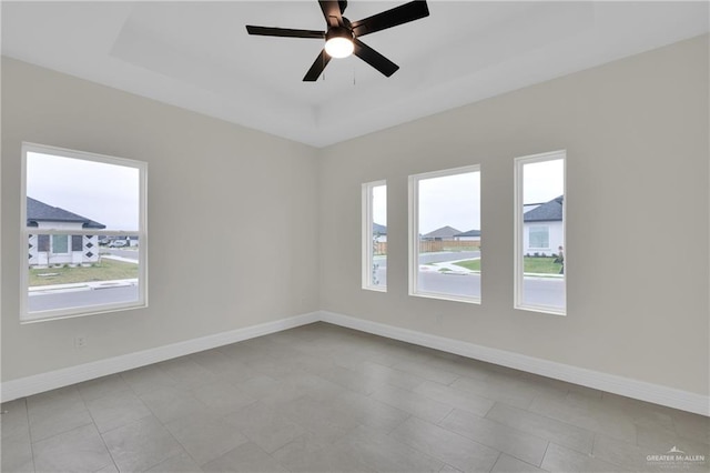 unfurnished room featuring ceiling fan, baseboards, and a raised ceiling