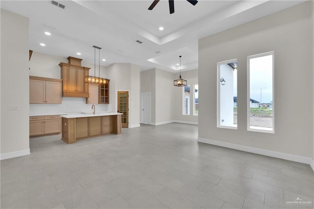 kitchen featuring light countertops, open floor plan, decorative light fixtures, and a center island with sink