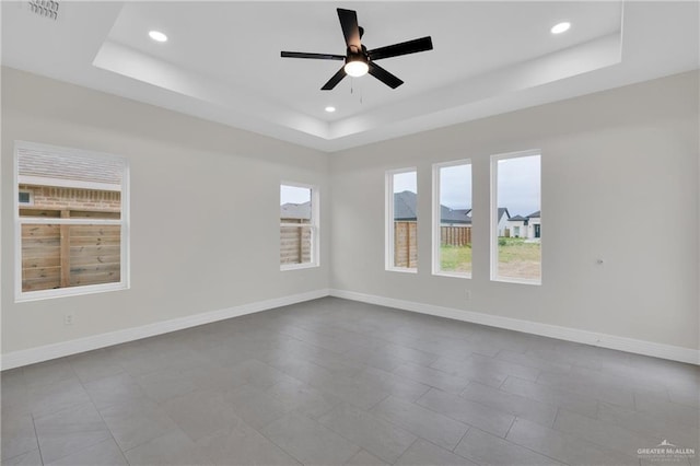 empty room with a ceiling fan, a tray ceiling, baseboards, and recessed lighting