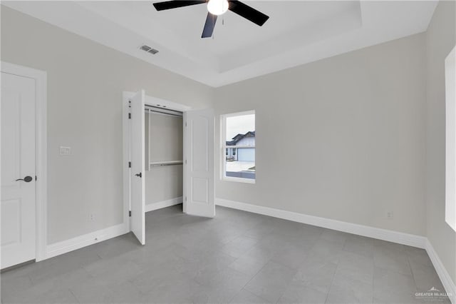 unfurnished bedroom featuring baseboards, visible vents, ceiling fan, and a tray ceiling