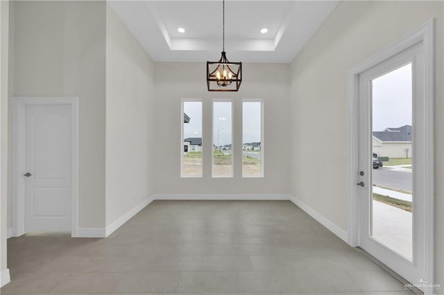 interior space featuring a notable chandelier, recessed lighting, a raised ceiling, and baseboards