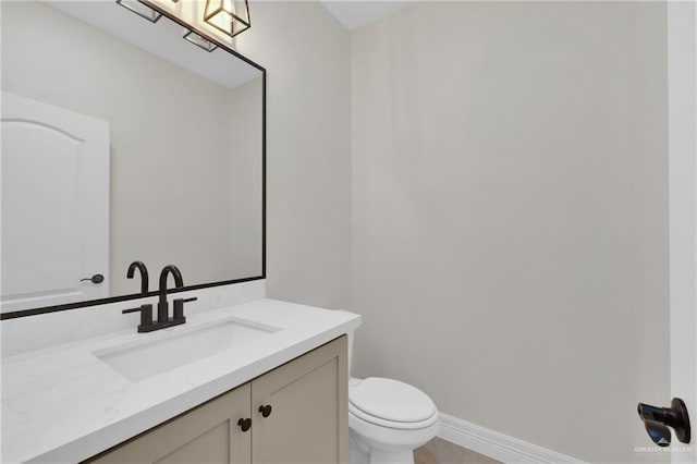 bathroom with toilet, baseboards, and vanity