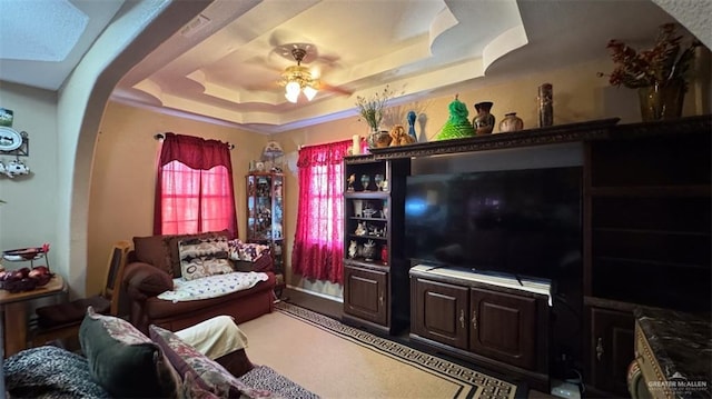 living room featuring a raised ceiling and ceiling fan