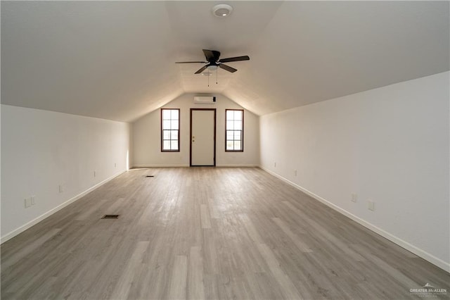 bonus room with ceiling fan, lofted ceiling, light hardwood / wood-style flooring, and an AC wall unit