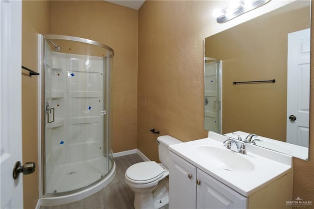 bathroom with hardwood / wood-style flooring, vanity, toilet, and a shower with shower door