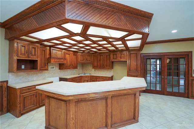 kitchen with light tile patterned flooring, a kitchen island, cooktop, crown molding, and french doors