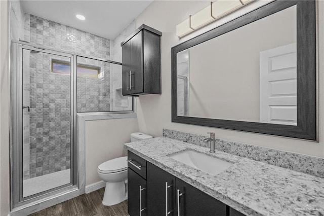 bathroom with vanity, a stall shower, toilet, and wood finished floors