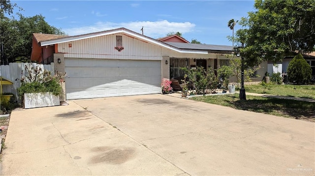 2104 Harvey St, Mcallen, TX 78501 - ranch-style home featuring fence, an attached garage, brick siding, solar panels, and driveway