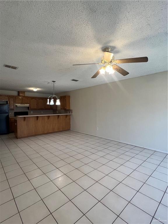 interior space with ceiling fan, light tile patterned floors, and a textured ceiling