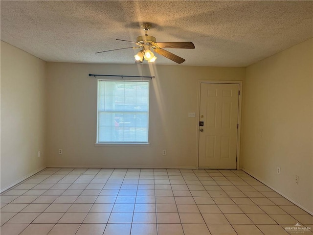 spare room with light tile patterned floors, a textured ceiling, and ceiling fan