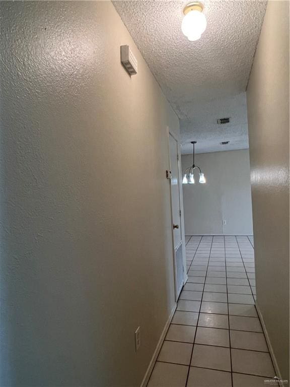 hall featuring light tile patterned floors and a textured ceiling