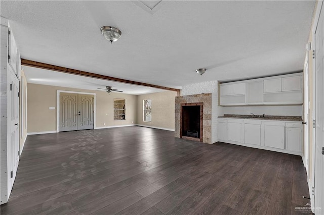 unfurnished living room featuring beamed ceiling, a large fireplace, and dark hardwood / wood-style floors