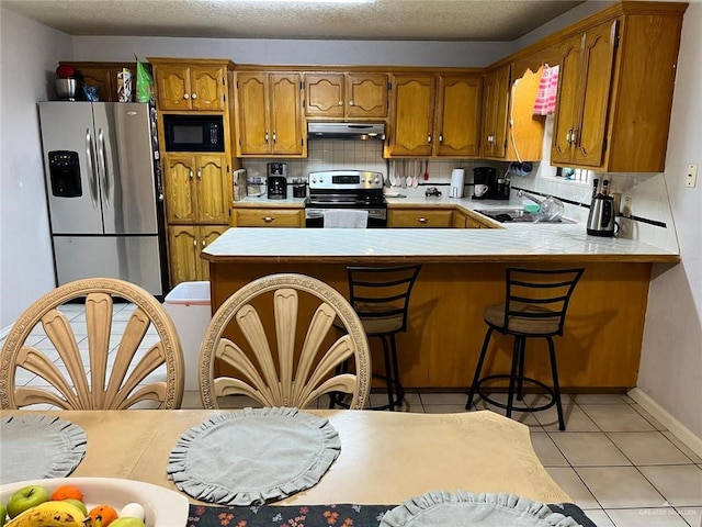 kitchen with backsplash, kitchen peninsula, sink, and appliances with stainless steel finishes