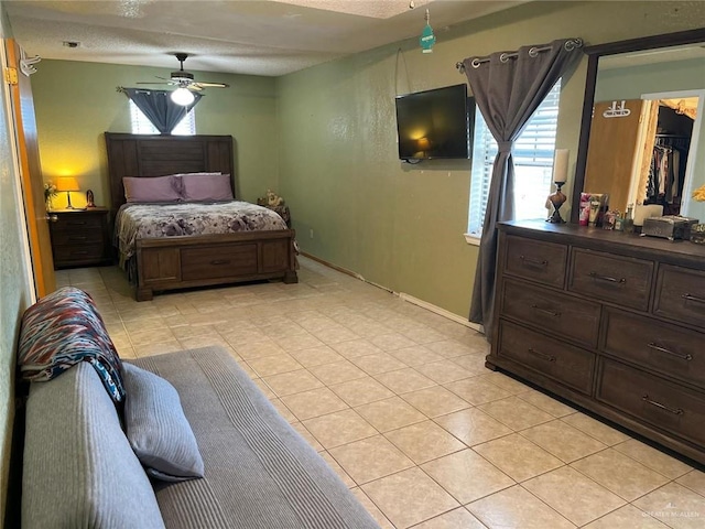 tiled bedroom featuring ceiling fan, a spacious closet, a textured ceiling, and a closet