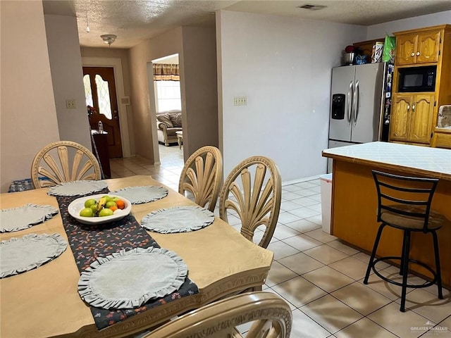 dining room featuring a textured ceiling and light tile patterned flooring