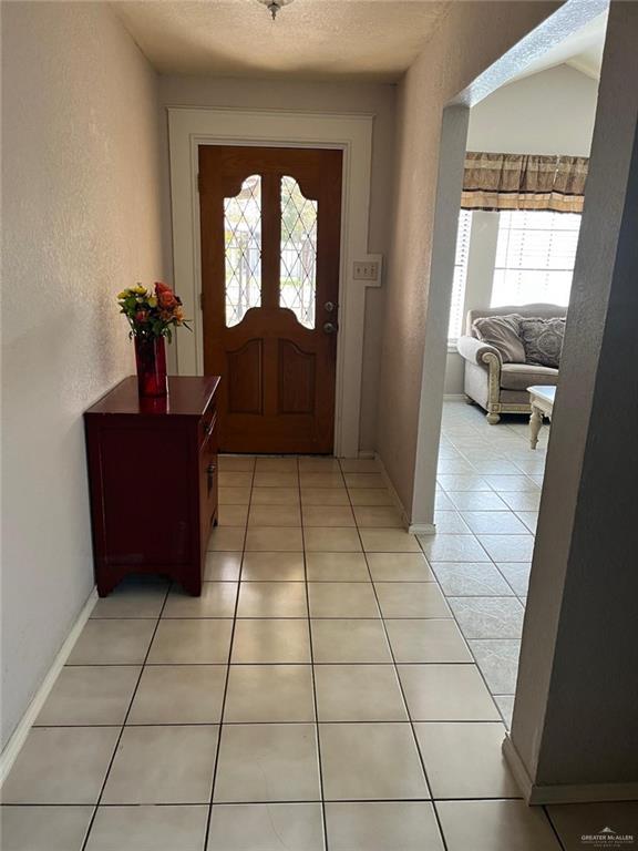 entryway featuring light tile patterned floors and a textured ceiling