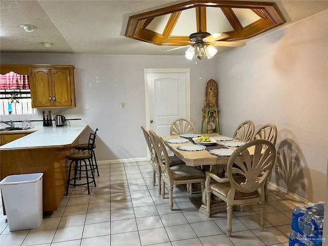 dining room featuring ceiling fan, sink, light tile patterned floors, and a textured ceiling