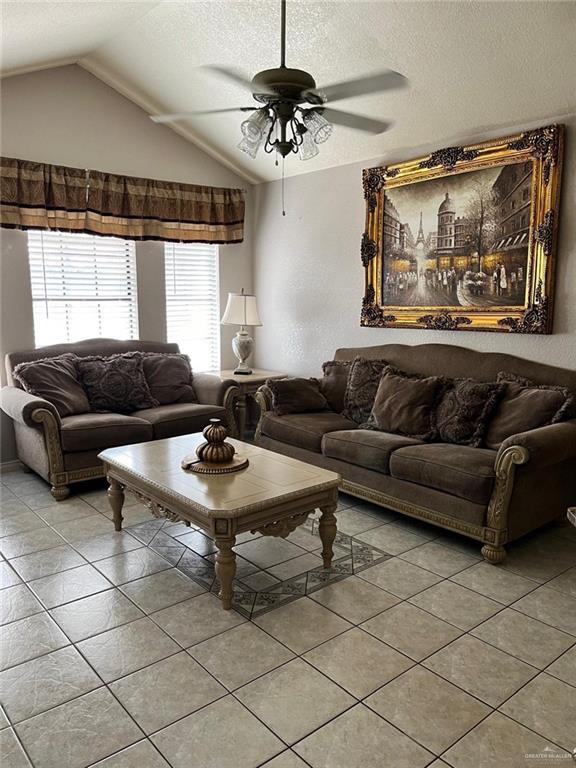 tiled living room with a textured ceiling, vaulted ceiling, and ceiling fan