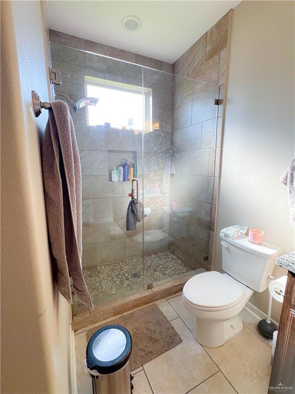 bathroom featuring a shower with door, vanity, tile patterned floors, and toilet