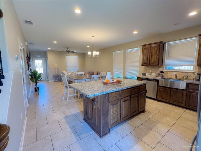 kitchen featuring dishwasher, light tile patterned floors, pendant lighting, a kitchen island, and sink