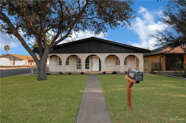 view of front facade featuring brick siding, covered porch, and a front yard