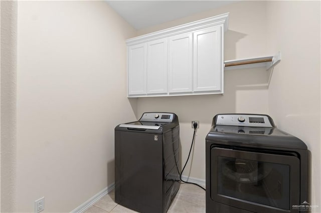 clothes washing area with cabinets, washer and dryer, and light tile patterned floors