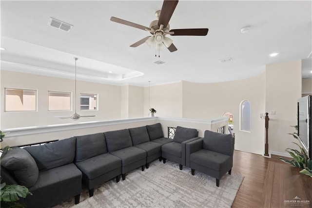 living room with ceiling fan, light hardwood / wood-style floors, and a tray ceiling