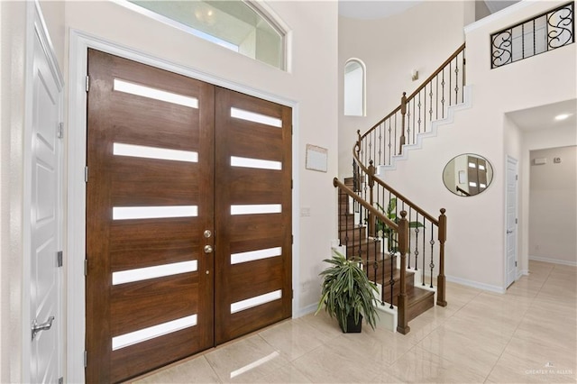 entryway featuring a towering ceiling, light tile patterned floors, and french doors