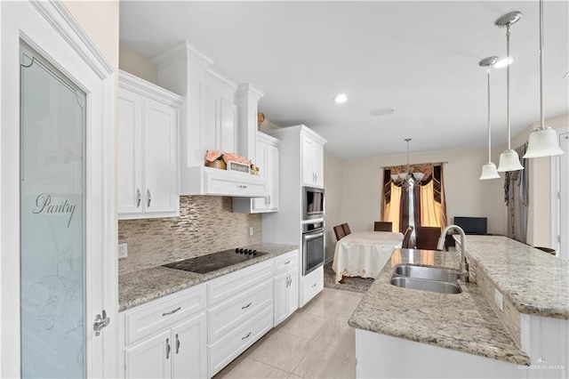 kitchen with appliances with stainless steel finishes, pendant lighting, white cabinetry, sink, and a center island with sink