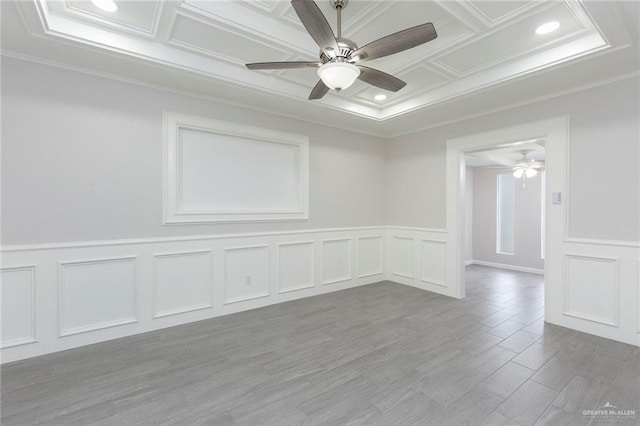 spare room with coffered ceiling, light hardwood / wood-style flooring, ornamental molding, and ceiling fan