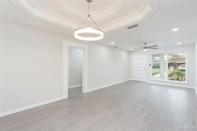 unfurnished room featuring crown molding, a tray ceiling, ceiling fan, and light wood-type flooring