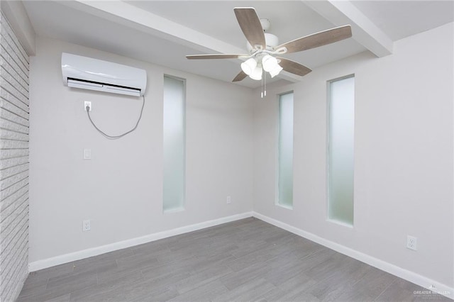 empty room with beamed ceiling, ceiling fan, wood-type flooring, and a wall mounted AC