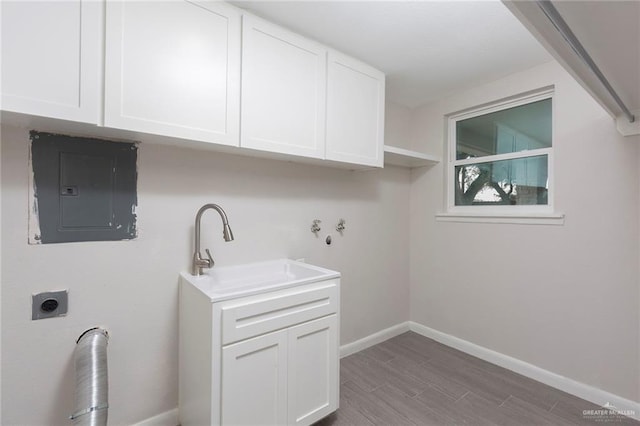 laundry area featuring sink, cabinets, wood-type flooring, electric panel, and hookup for an electric dryer