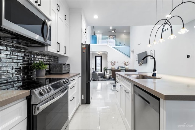 2215 Corales St, Mission, TX 78573 - kitchen featuring appliances with stainless steel finishes, tasteful backsplash, white cabinetry, recessed lighting, and a center island with sink